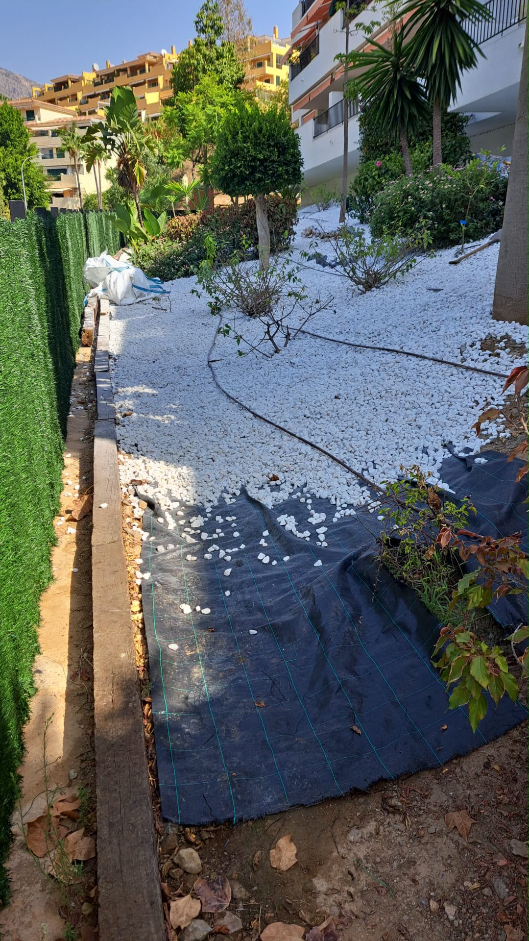 Colocación de grava blanca y malla en una zona ajardinada