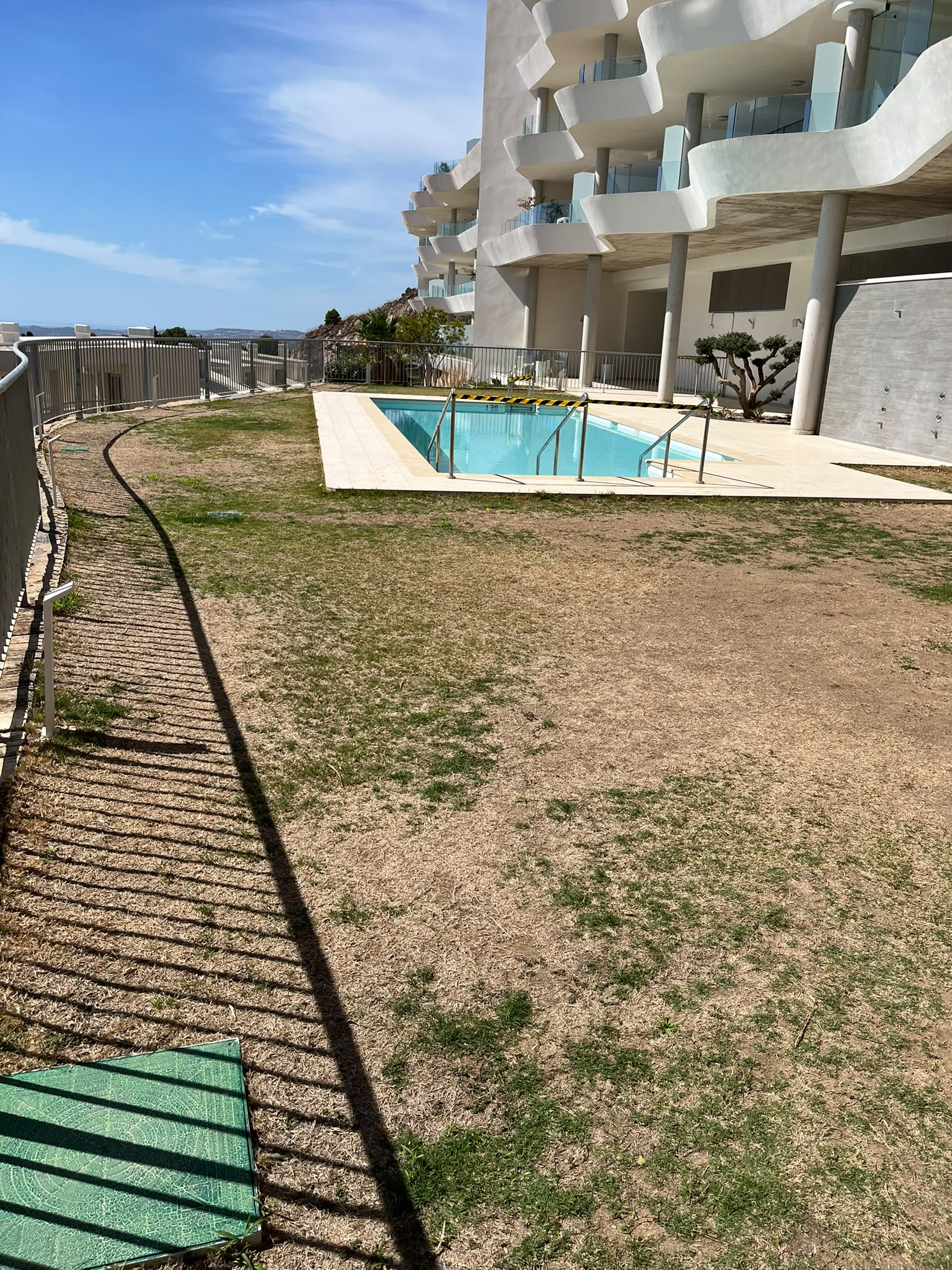 Césped deteriorado junto a la piscina de una comunidad, antes de su recuperación