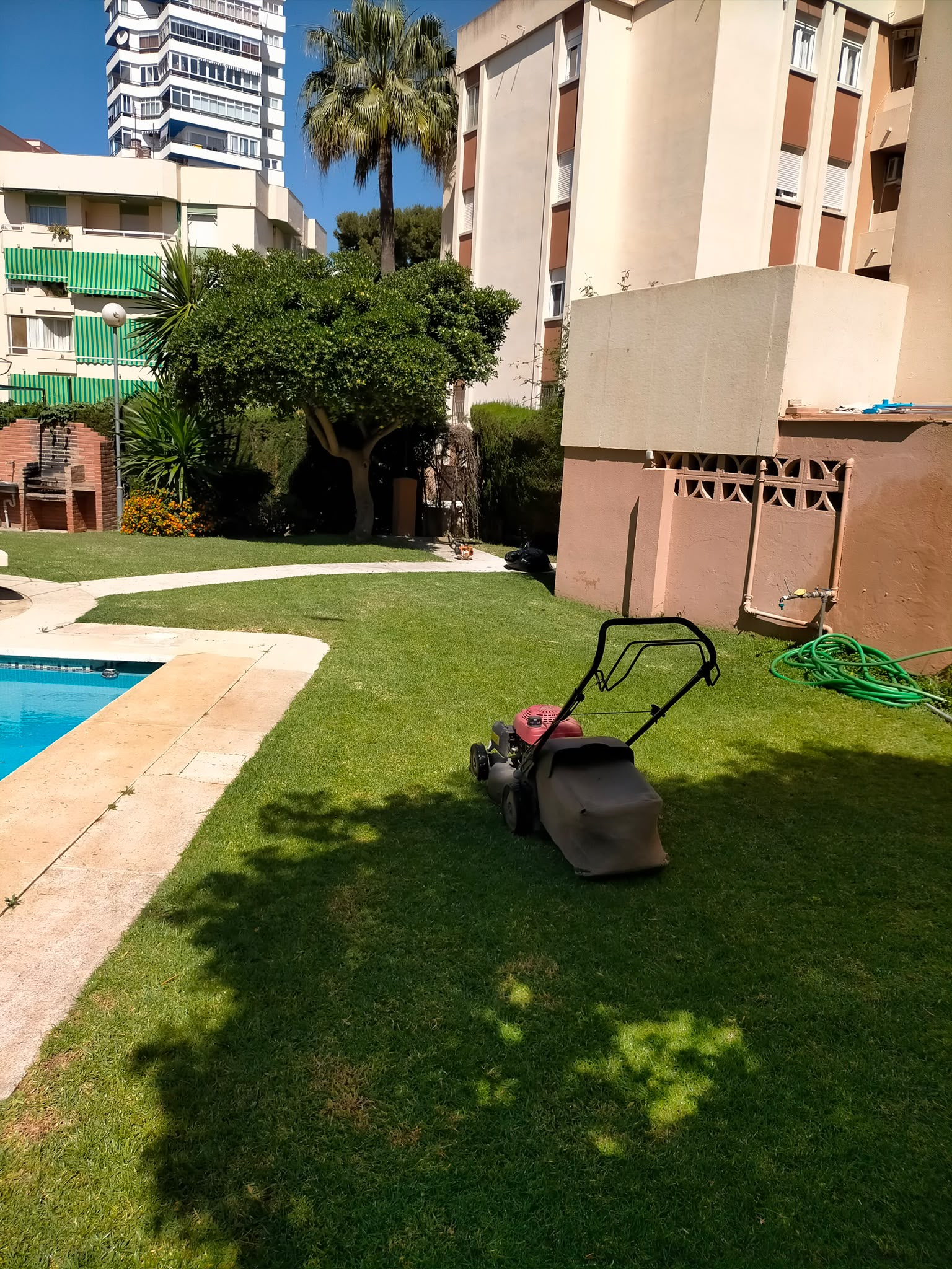 Cortacésped en las zonas verdes de una comunidad junto a una piscina