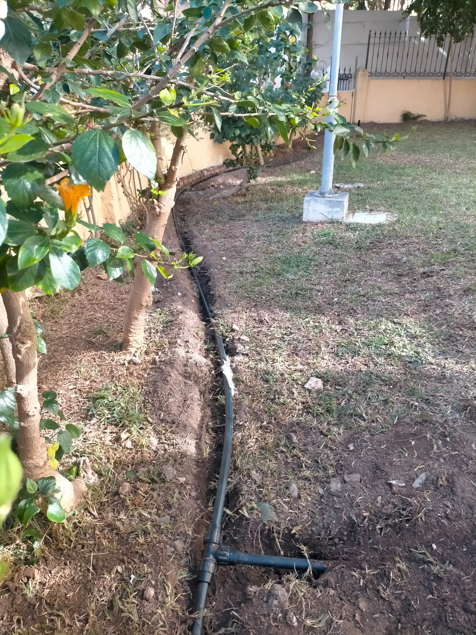Tubería de riego instalada en una zanja junto al jardín